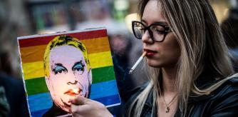 A woman lights a cigarette placed in a placard depicting Hungary's Prime Minister Viktor Orban, during a demonstration
